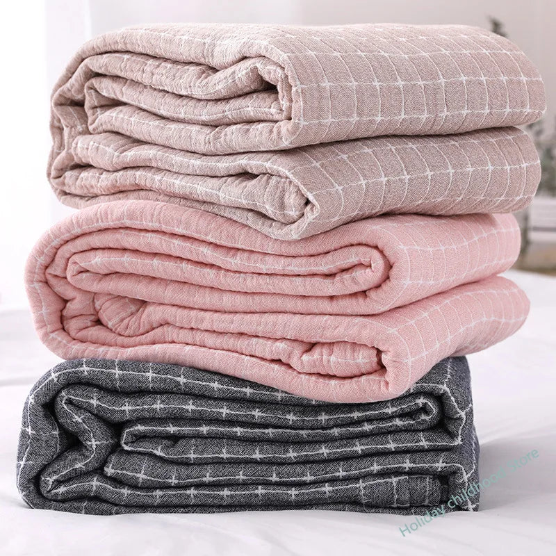 Gestapelte karierte Decken in Beige, Rosa und Grau, weiche Baumwolle, gemütliche Wohntextilien.