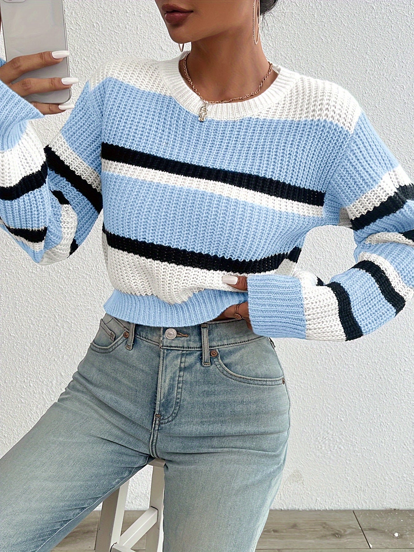 Frau trägt gestreiften Pullover in Blau-Weiß, Jeans, modisch, lässig, Strickmode, Herbst.