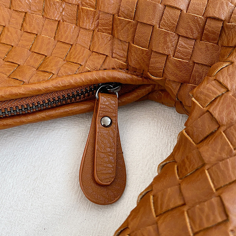 Geflochtene braune Ledertasche mit Reißverschluss, Nahaufnahme, modisches Accessoire.