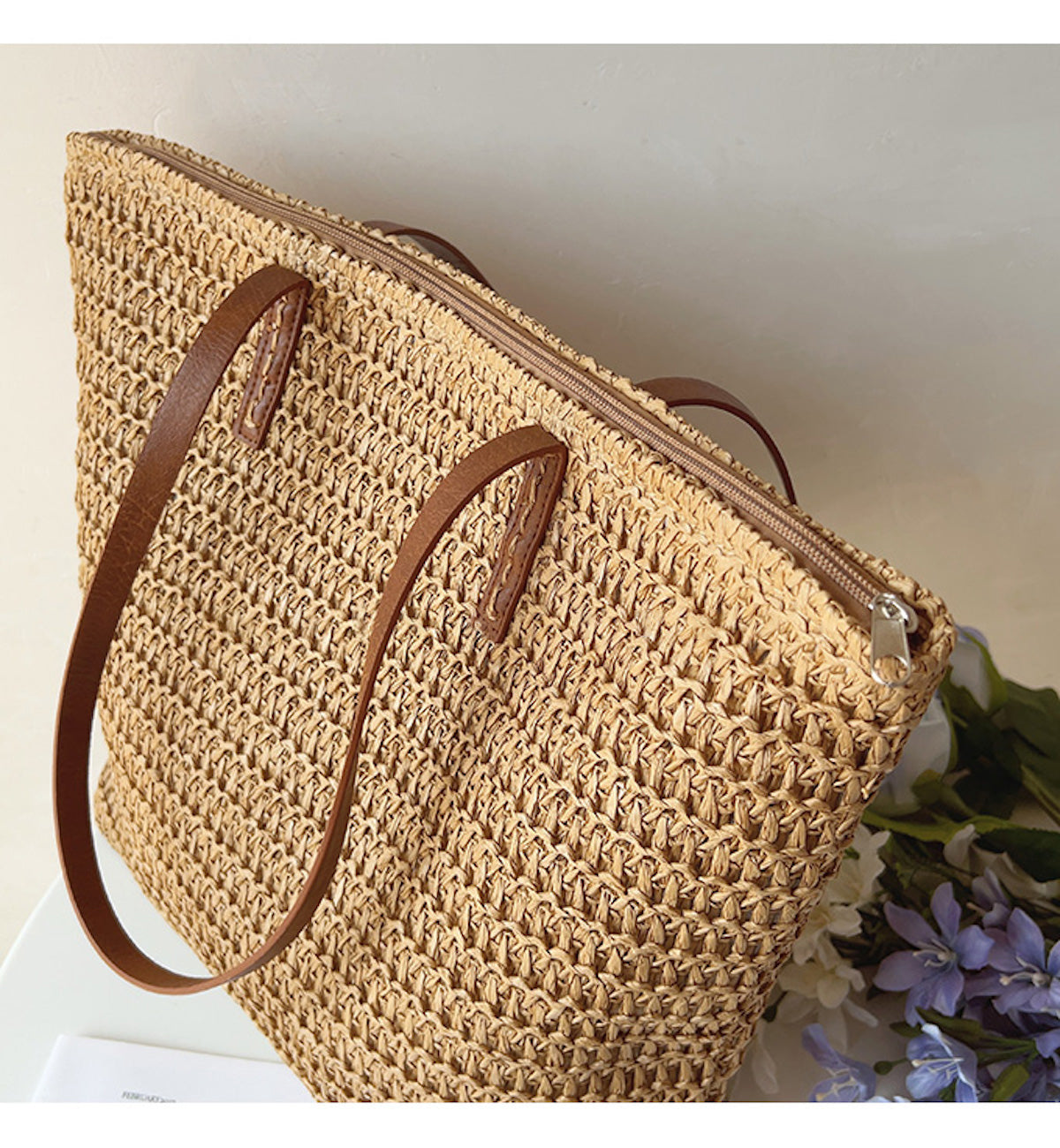 Geflochtene Strohtasche mit braunen Ledergriffen, ideal für Sommer und Strand.