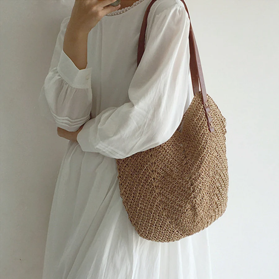 Frau in weißem Kleid mit brauner Strohtasche, modisch, Sommeraccessoire, lässiger Stil.