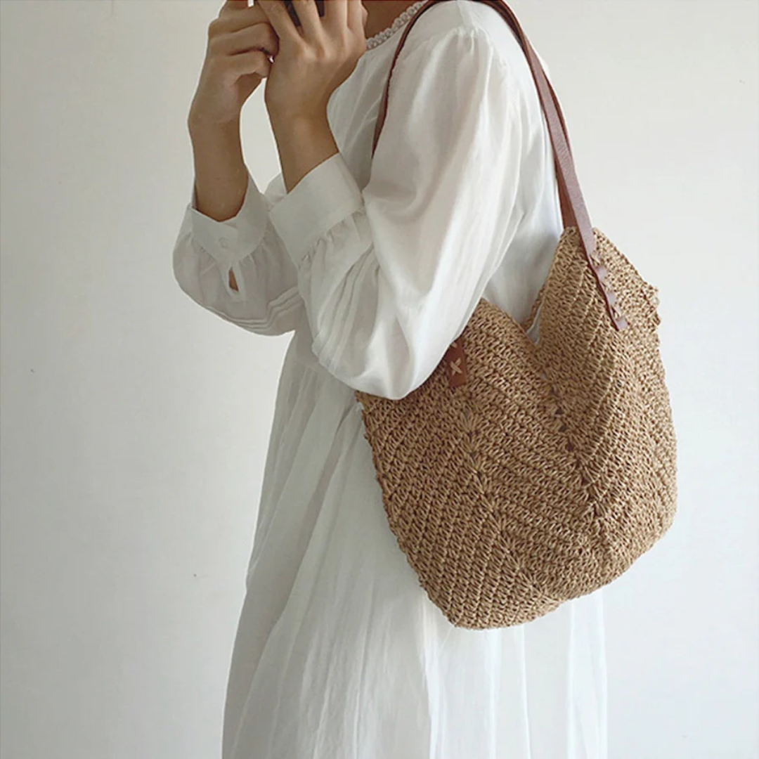Frau mit weißem Kleid trägt braune Strohtasche, modisches Accessoire, Sommerstil.