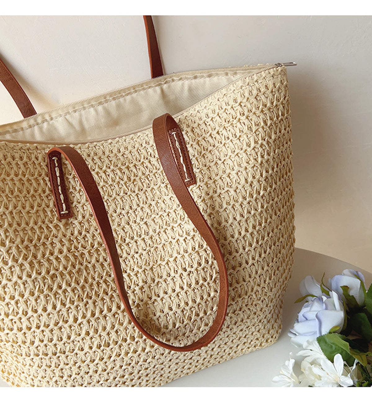 Geflochtene Strohtasche mit braunen Ledergriffen, ideal für Sommer und Strand.
