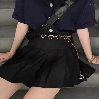 Frau in schwarzem Faltenrock mit Herz-Gürtel, schwarze Bluse, modisches Outfit, Treppe.