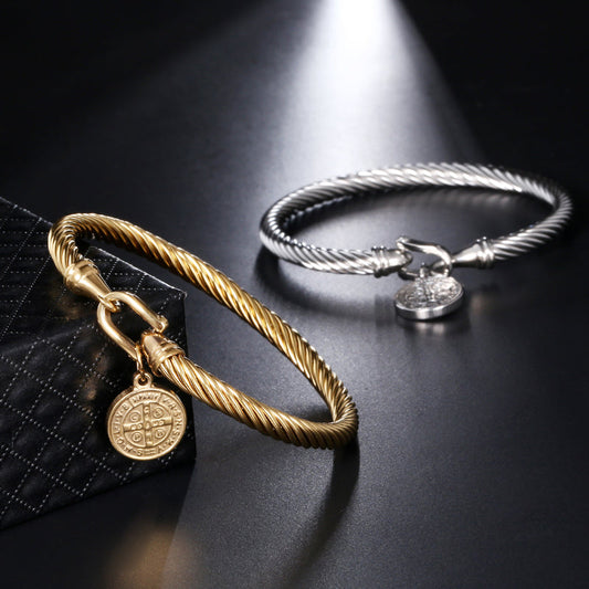 Zwei Armbänder aus Edelstahl, gold und silber, mit Medaillon, auf schwarzem Hintergrund.