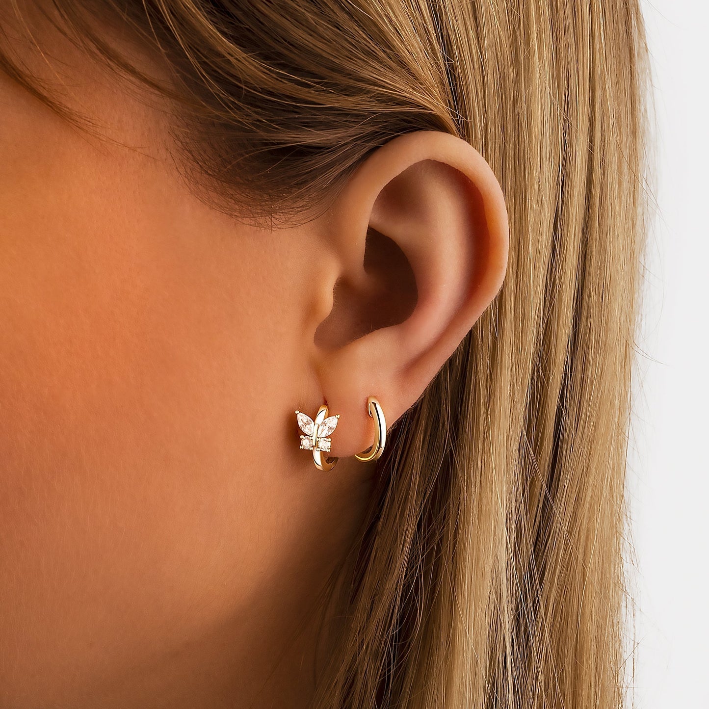 Frau mit goldenen Ohrringen, Blattdesign, Zirkonia, Schmuck, Nahaufnahme, eleganter Stil.