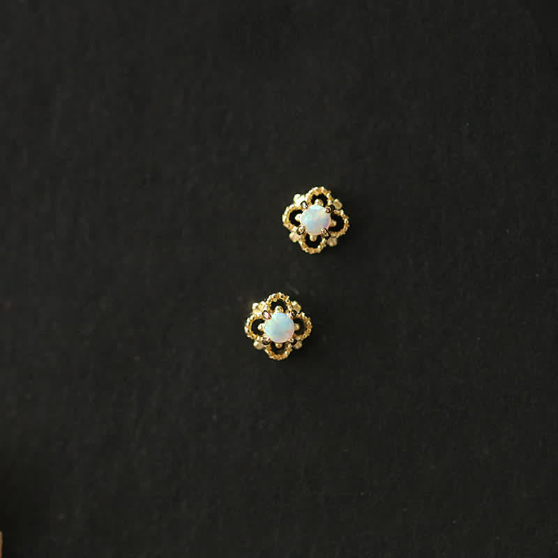 Goldene Ohrringe mit Opal, Blumenform, eleganter Schmuck, Damenaccessoire, schwarzer Hintergrund.