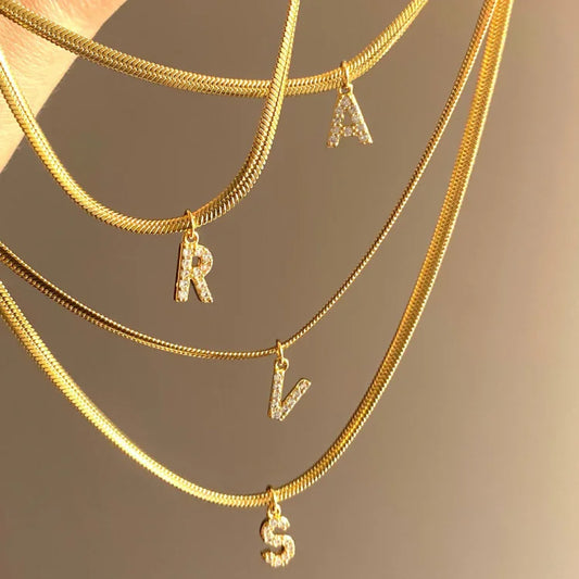 Goldene Halsketten mit Buchstabenanhängern R, A, V, S, glänzend, modisch, Schmuckaccessoire.