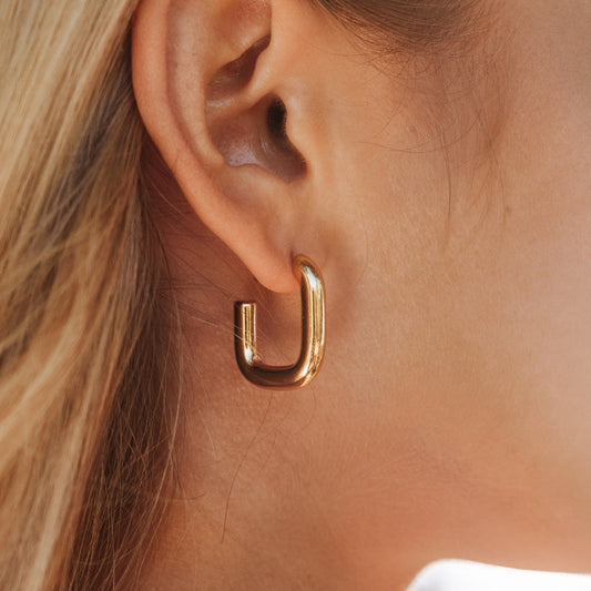 Goldene Creolen-Ohrringe, glänzend, modern, an Ohr getragen, Schmuck für Damen.