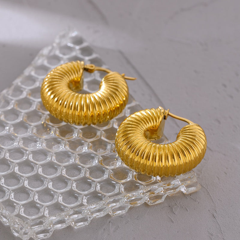 Goldene Creolen Ohrringe auf Glas, geriffelt, modisch, Schmuck, Damenaccessoire.