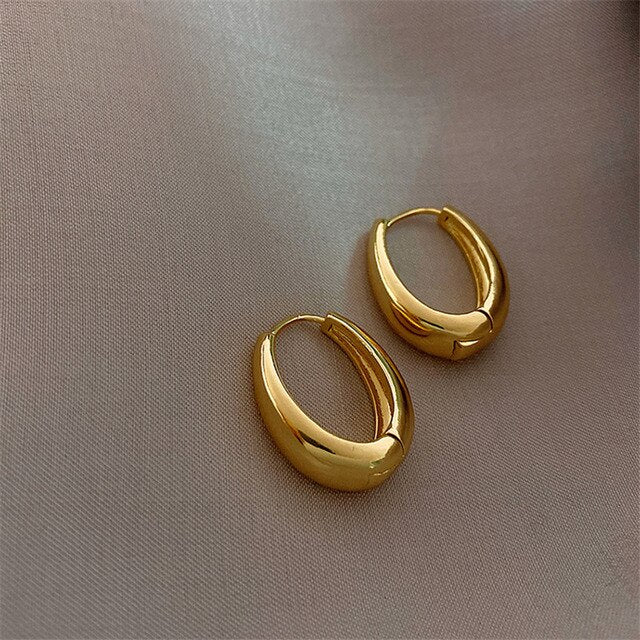 Goldene Creolen Ohrringe auf Stoff, elegantes Schmuckdesign, modische Accessoires.