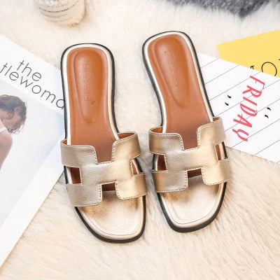 Goldene Damen-Sandalen, flach, Leder, modisch, bequem, Sommermode, auf Teppich.