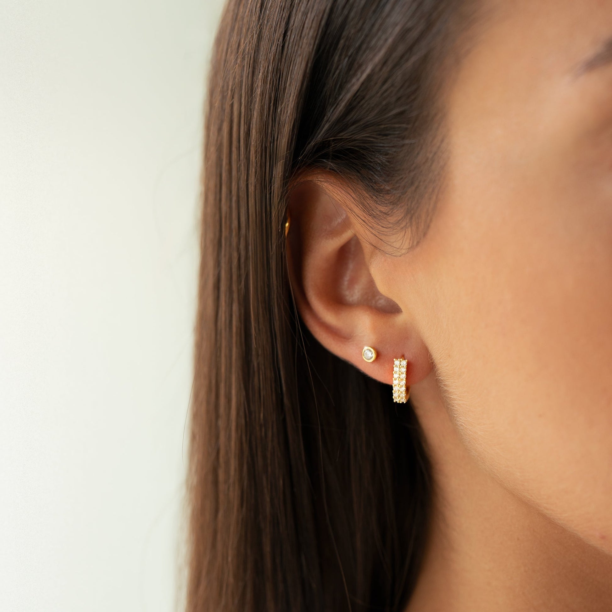Frauenohr mit goldenen Ohrringen, Diamantstecker, Nahaufnahme, eleganter Schmuck, Modeaccessoire.