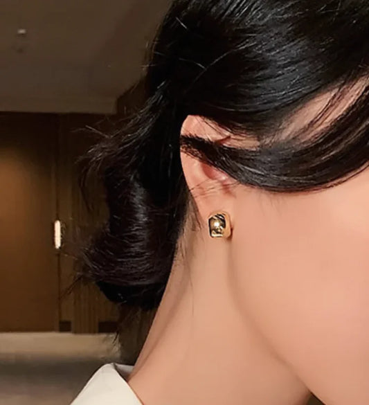 Frau mit elegantem, quadratischem, goldfarbenem Ohrring, Nahaufnahme, modisches Accessoire.