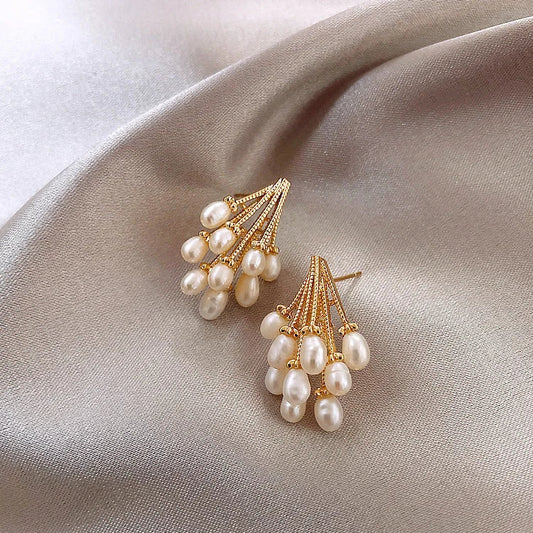 Goldene Ohrringe mit weißen Perlen auf beigem Satin, eleganter Schmuck, modische Accessoires.