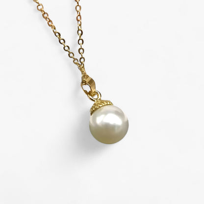 Goldene Halskette mit weißem Perlenanhänger, eleganter Schmuck, Damenaccessoire.