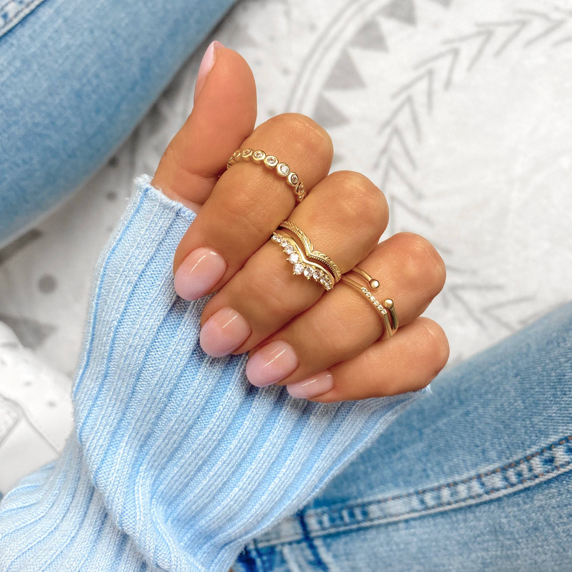 Frau mit goldenen Ringen, Strickpullover, Jeans, modischer Schmuck, Nahaufnahme.