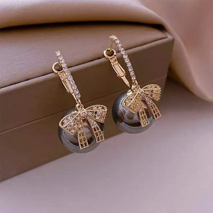 Goldene Ohrringe mit Schleifen und Perlen, luxuriöses Schmuckdesign, Damenaccessoire.