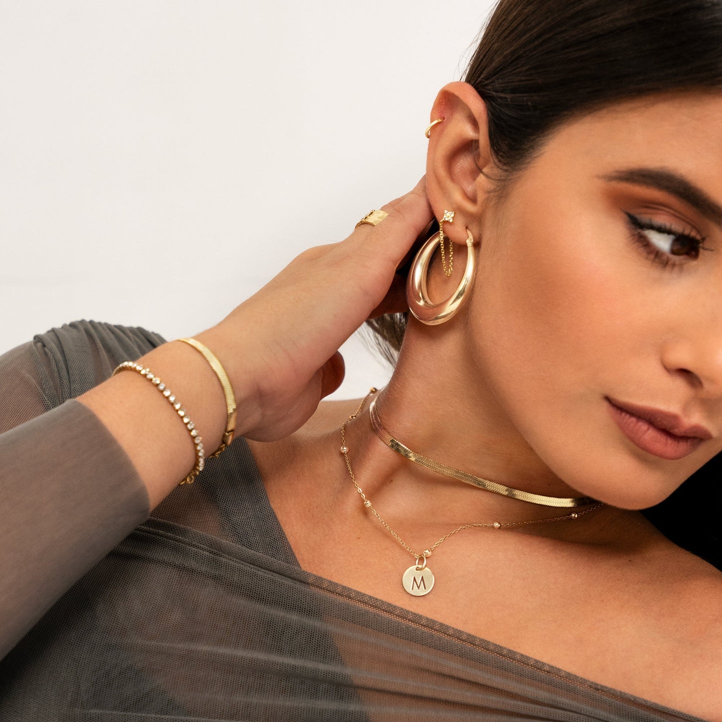 Frau mit goldenen Ohrringen, Halsketten und Armbändern, Schmuckmode, eleganter Stil.