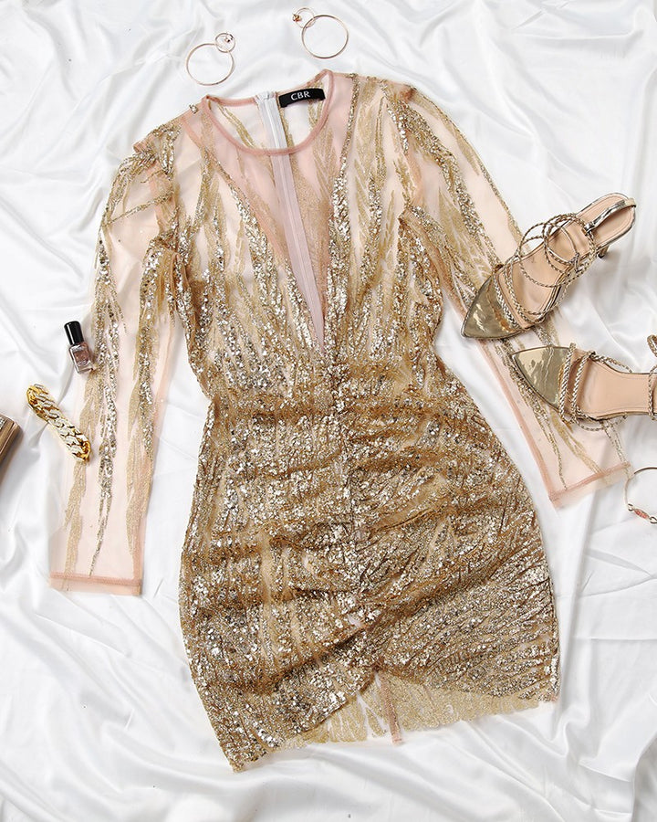 Goldenes Paillettenkleid mit transparenten Ärmeln auf weißem Hintergrund, elegante Abendmode.