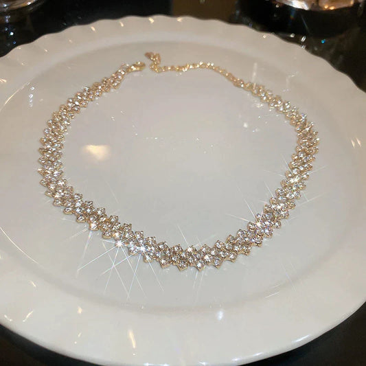 Goldene Halskette mit funkelnden Kristallen auf weißem Teller, eleganter Schmuck für Damen.