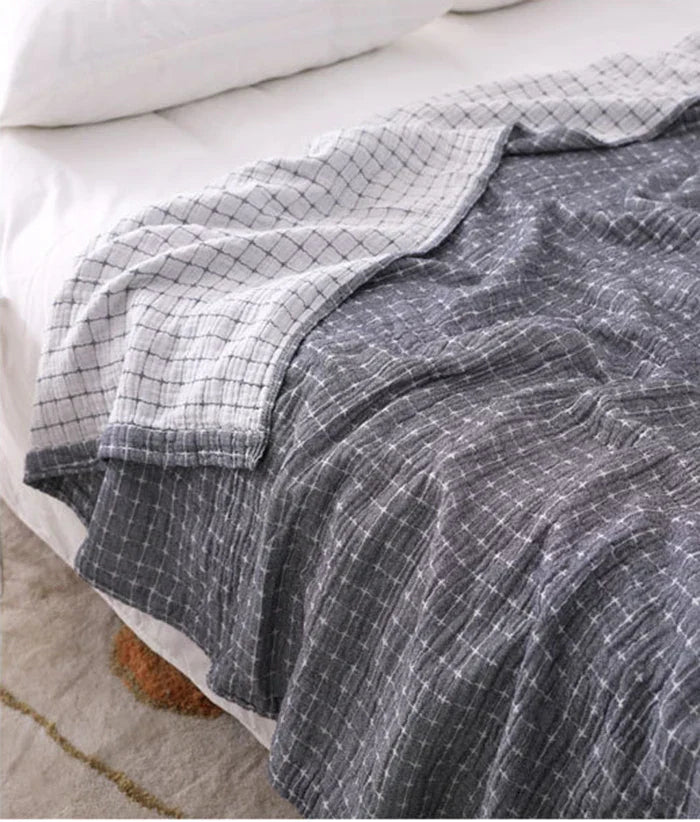 Graue karierte Bettdecke aus Baumwolle auf einem Bett, gemütlich und modern.