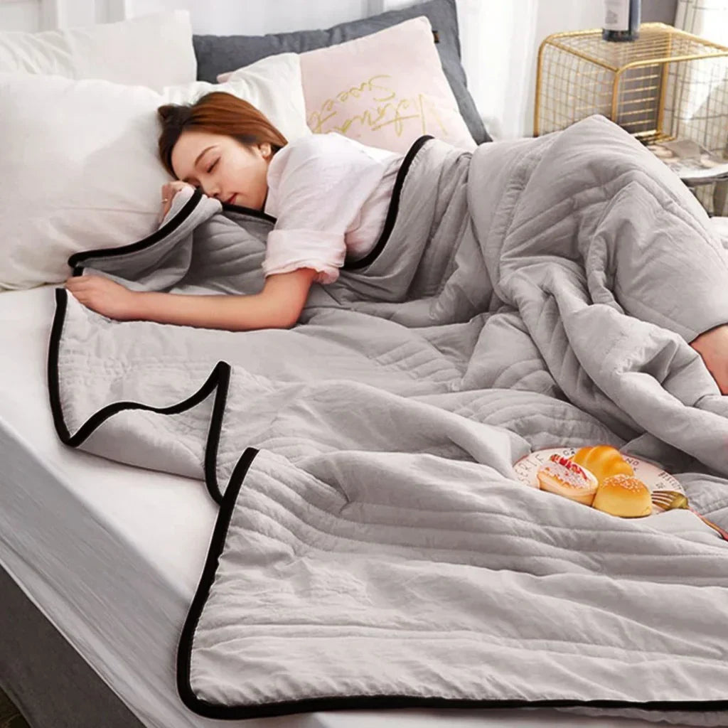Frau schläft unter grauer Bettdecke, gemütliches Schlafzimmer, moderne Einrichtung, Entspannung.
