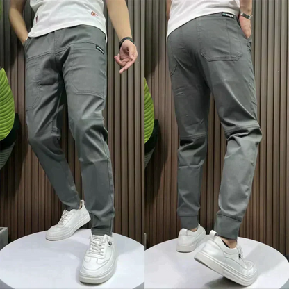 Graue Herren-Chinohose, Slim Fit, Baumwolle, lässig, mit weißen Sneakern kombiniert.