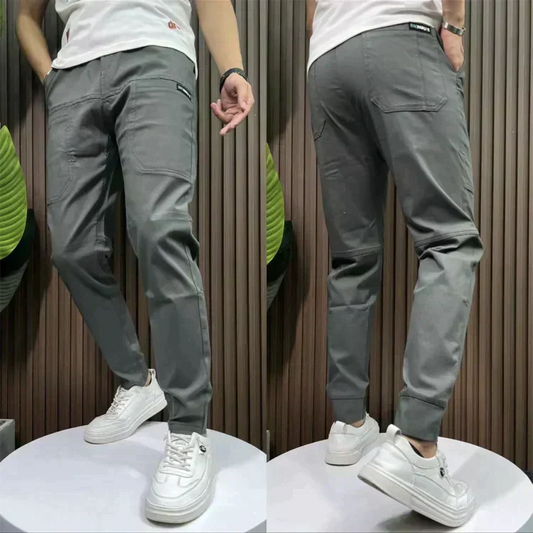 Graue Herren-Chinohose, Slim Fit, Baumwolle, lässig, mit weißen Sneakern kombiniert.