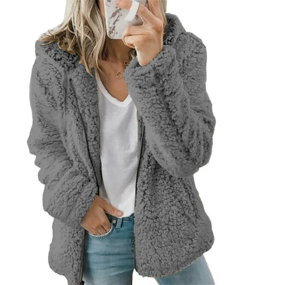 Frau in grauer Teddyjacke, weißem T-Shirt und Jeans, modische Winterbekleidung.