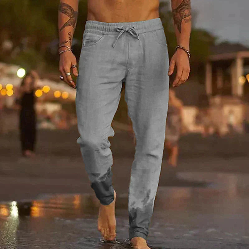 Mann in grauer Jogginghose am Strand, lässige Sportbekleidung, Sommermode, Herrenmode.