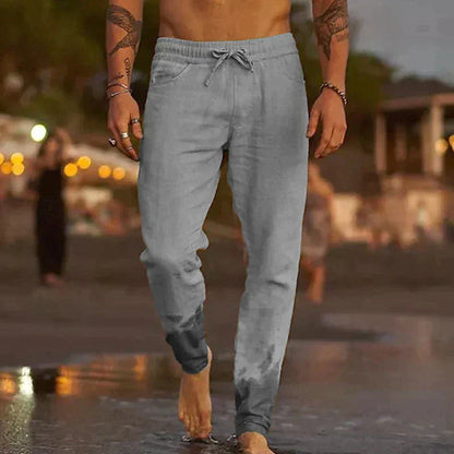 Mann in grauer Jogginghose am Strand, lässige Sportbekleidung, Sommermode, Herrenmode.