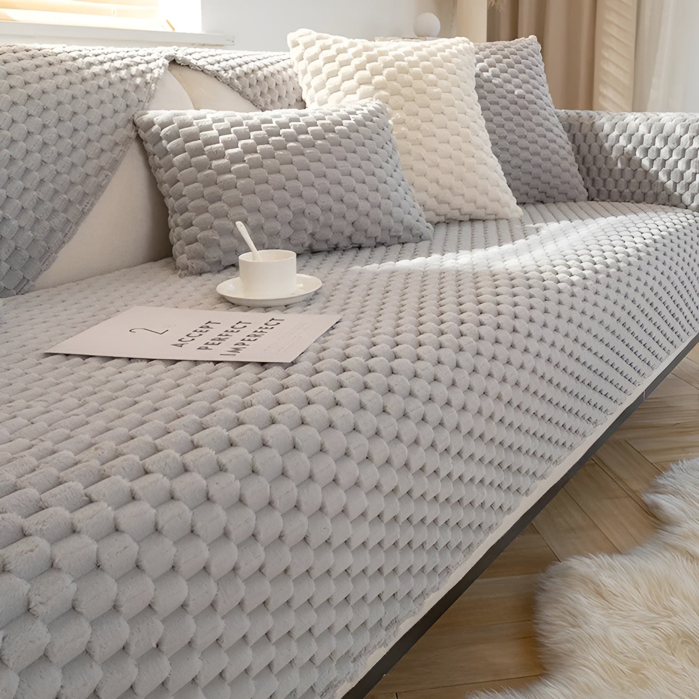 Graues Sofa mit strukturierter Oberfläche, passenden Kissen, Kaffeetasse und Notizbuch im Wohnzimmer.