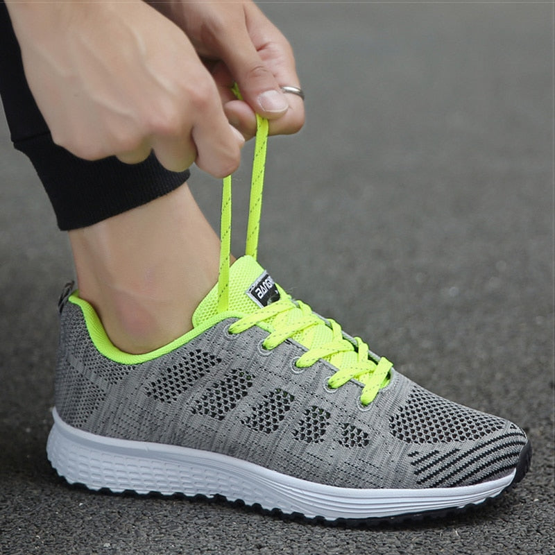 Grauer Sportschuh mit neongelben Schnürsenkeln, atmungsaktives Mesh, ideal für Laufen.