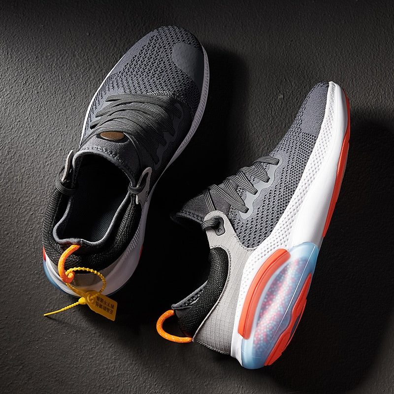 Graue Sportschuhe mit roter Sohle, atmungsaktives Mesh, ideal für Laufen und Fitness.