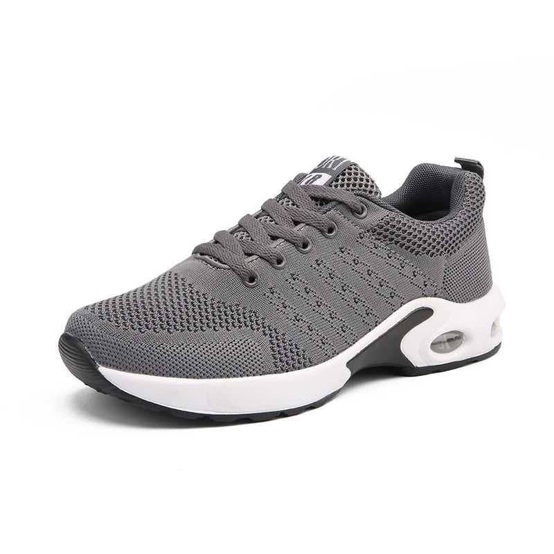 Grauer Sportschuh, atmungsaktives Mesh, rutschfeste Sohle, ideal für Laufen und Fitness.