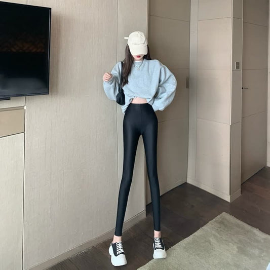 Frau in grauem Pullover und schwarzen Leggings, trägt weiße Sneaker und beige Kappe.