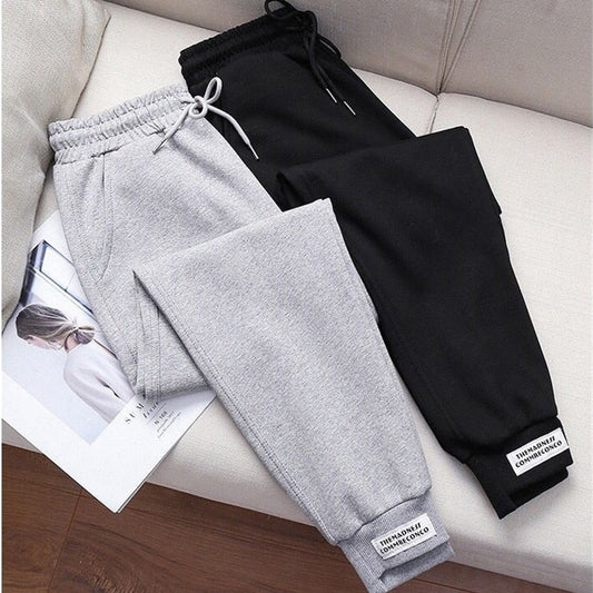 Graue und schwarze Jogginghosen aus Baumwolle auf Sofa, bequeme Sportbekleidung für Damen.