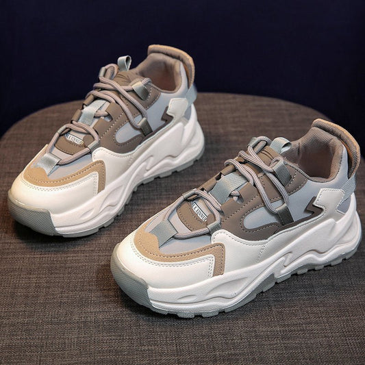 Graue und weiße Chunky Sneaker, Leder, modisch, sportlich, Unisex, auf grauem Hintergrund.