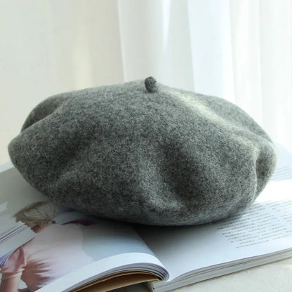 Graue Woll-Baskenmütze auf offenem Buch, stilvolles Accessoire, modisch, elegant.
