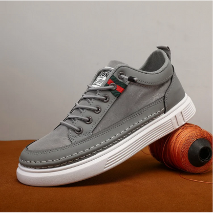 Grauer Sneaker aus Leder mit weißer Sohle, modisches Design, Herrenschuh, seitliche Ansicht.