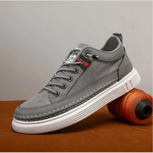 Grauer Sneaker aus Leder mit weißer Sohle, modisches Design, Herrenschuh, seitliche Ansicht.