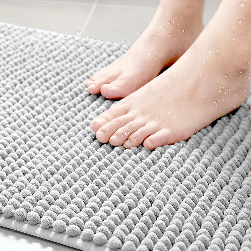 Grauer rutschfester Badezimmerteppich, saugfähig, weiche Textur, Füße, Wassertröpfchen.