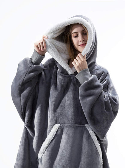 Frau in grauem, flauschigem Oversize-Hoodie mit Kapuze und Kängurutasche.