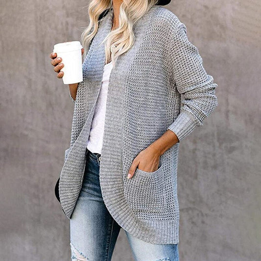 Frau in grauem Strickcardigan mit Kaffeebecher, lässige Mode, Herbstoutfit, Jeans.