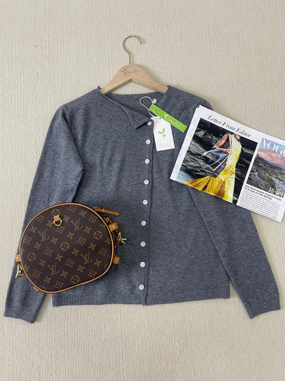 Grauer Cardigan mit Knöpfen, Louis Vuitton Tasche, Vogue-Magazin auf beigem Hintergrund.