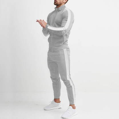 Mann in grauem Trainingsanzug mit weißen Streifen, sportlich, modern, Freizeitkleidung.