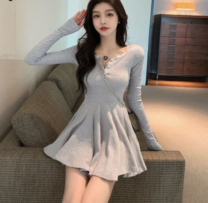Frau in grauem Langarm-Kleid, sitzt auf Sofa, modisch, elegant, Freizeitkleidung, Wohnzimmer.