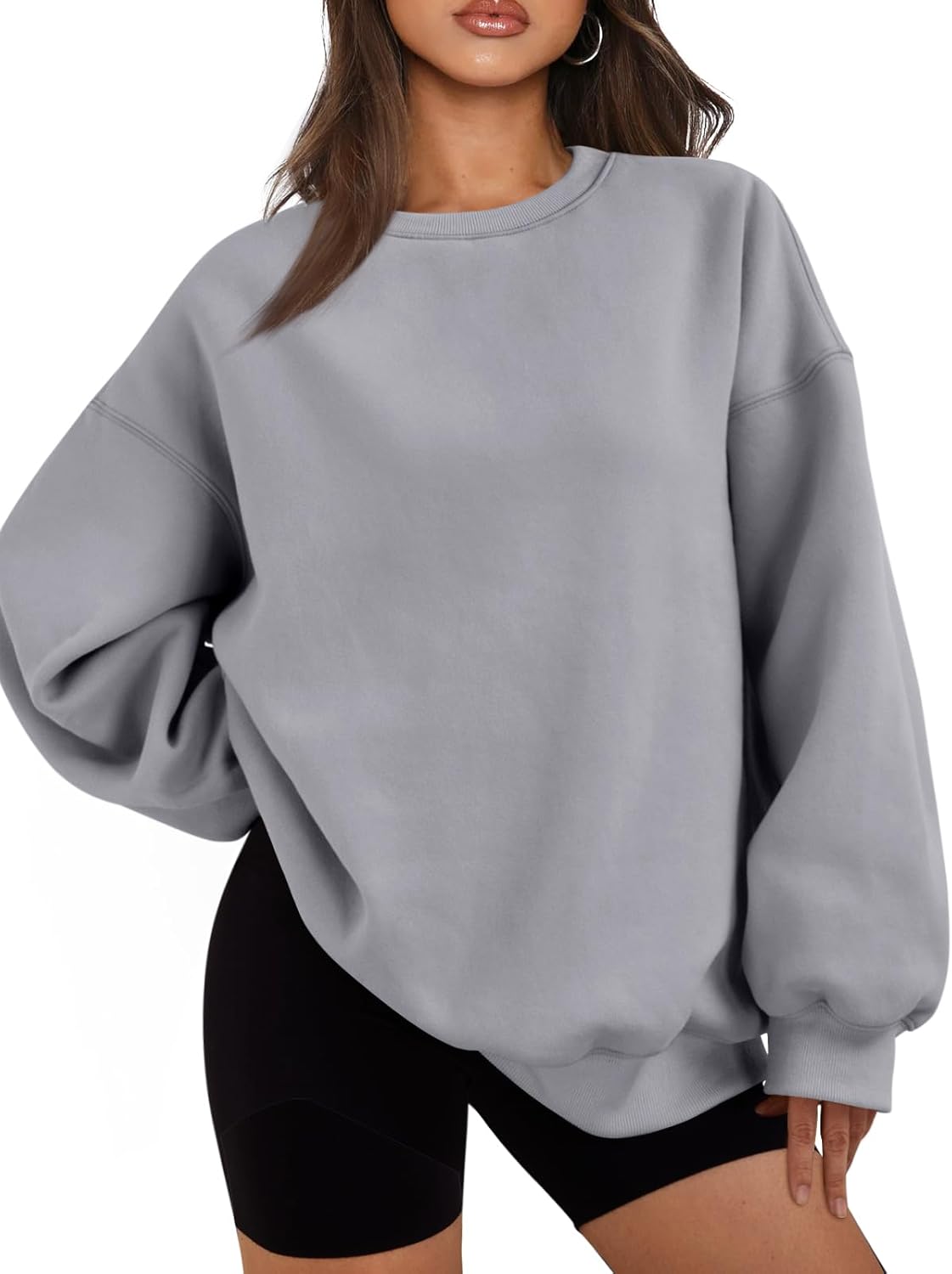 Frau in grauem Oversize-Sweatshirt und schwarzen Shorts, lässige Mode, bequeme Kleidung.