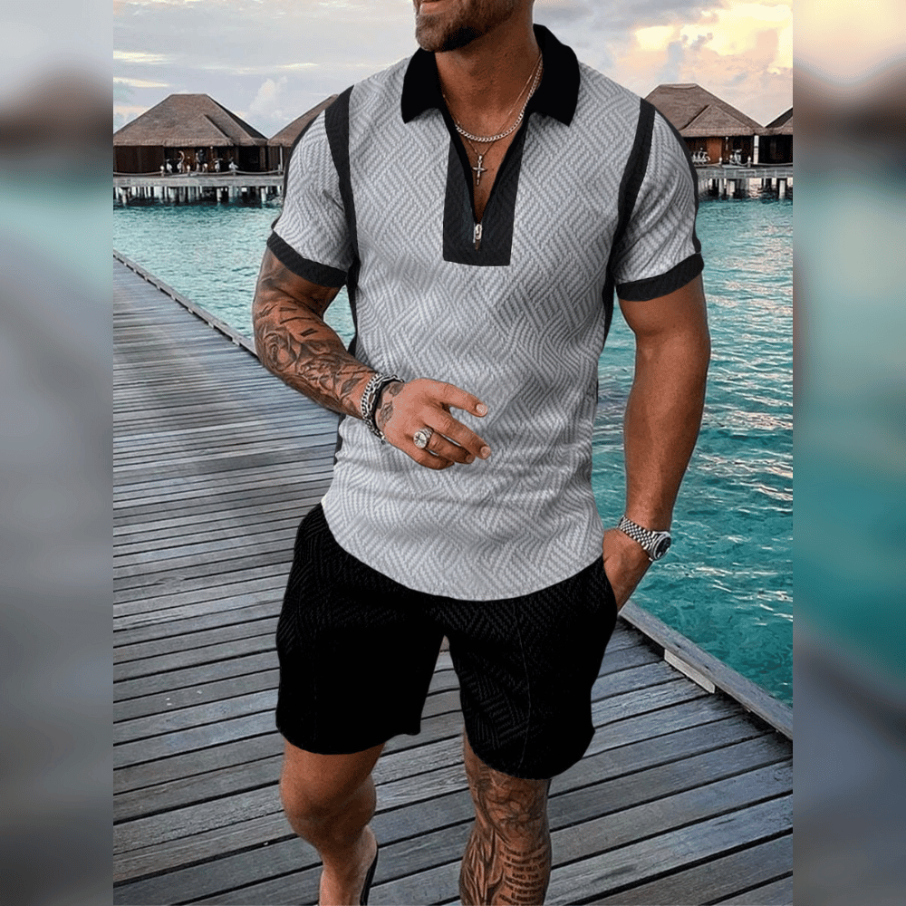 Mann in grauem Poloshirt und schwarzen Shorts auf Holzsteg am Meer, Sommermode, Urlaub.